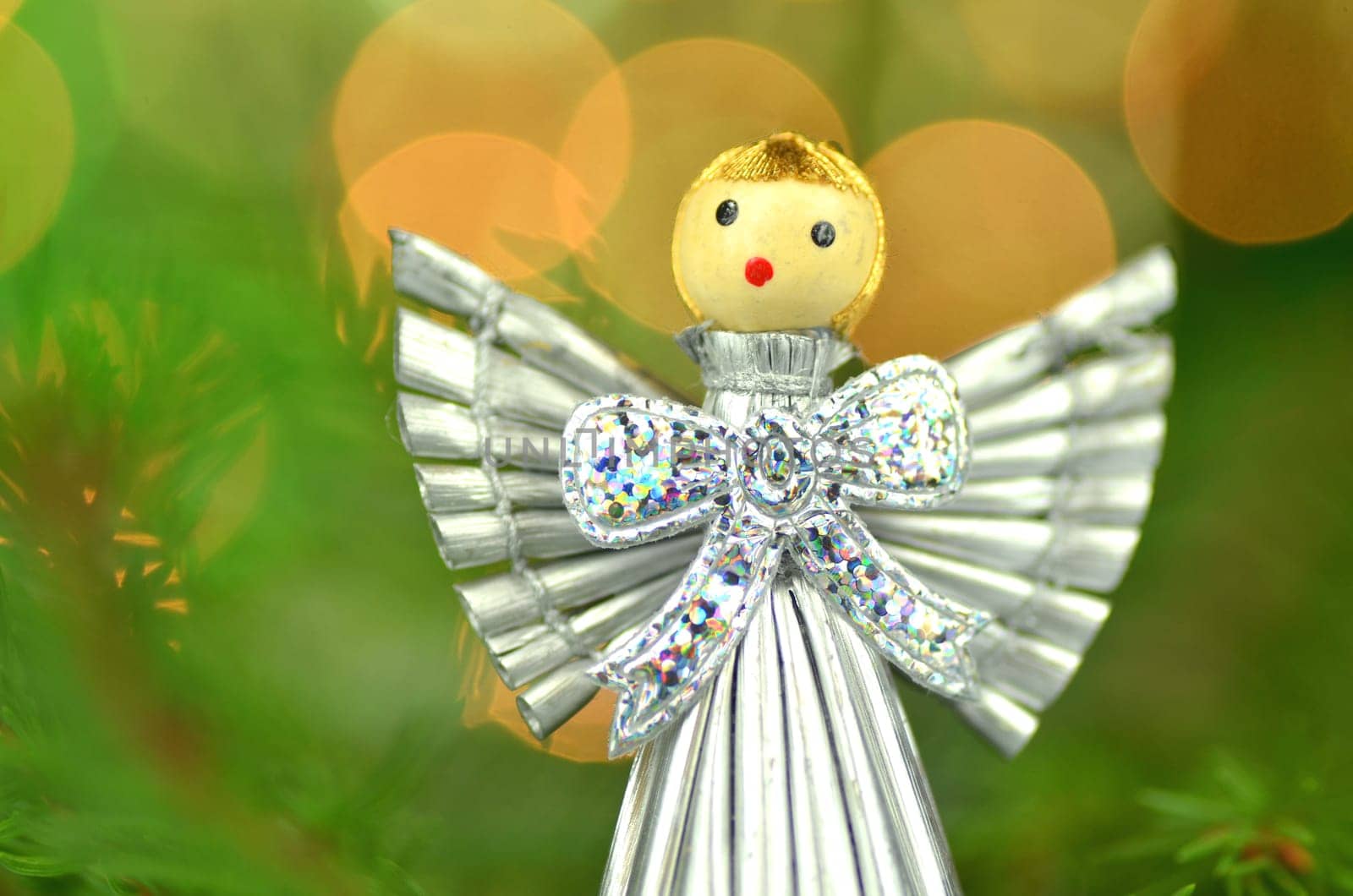 christmas decoration, silver angel made of straw against bokeh background
