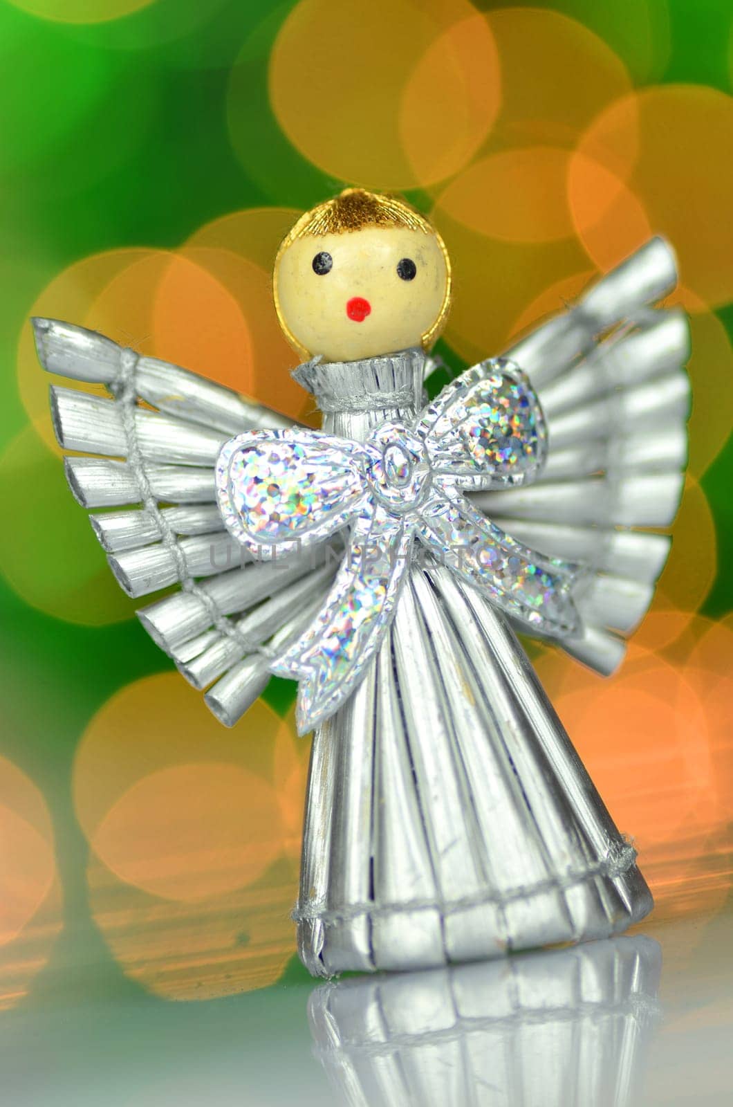 christmas decoration, silver angel made of straw against bokeh background
