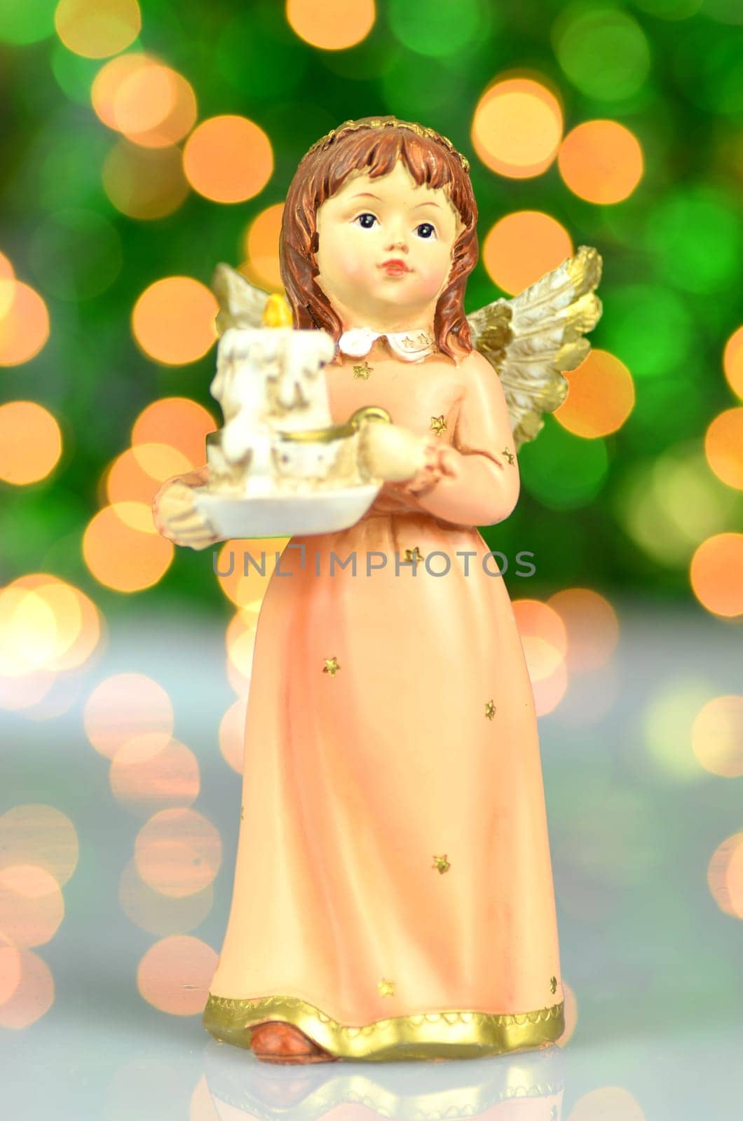 christmas decoration, figure of angel holding a candle against bokeh background