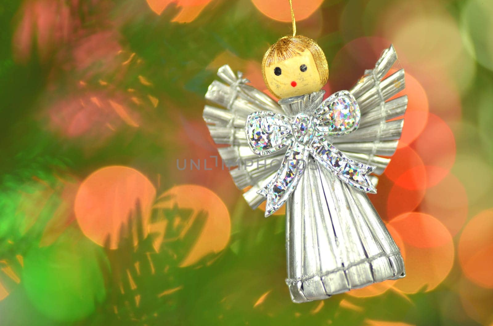 christmas decoration, silver angel made of straw against bokeh background