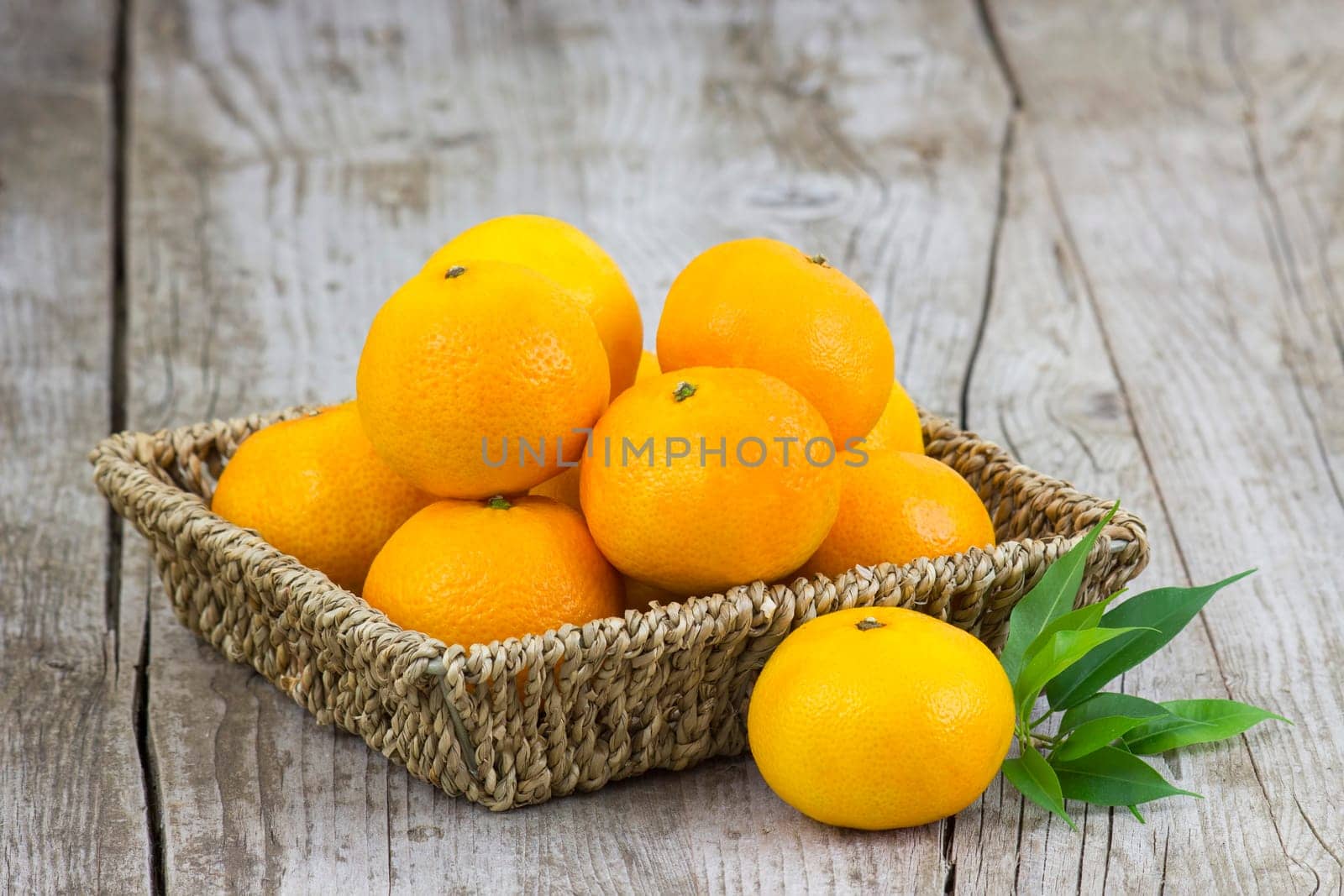 fresh tangerines in a basket on old wooden background