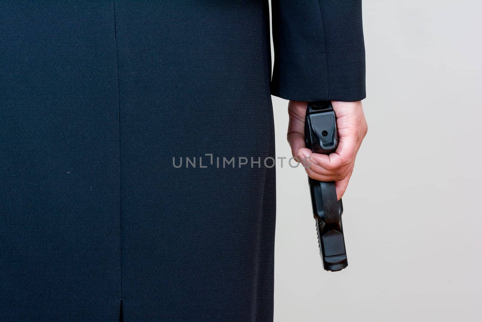 Close up of a the back side of a woman in business suit holding a hand gun