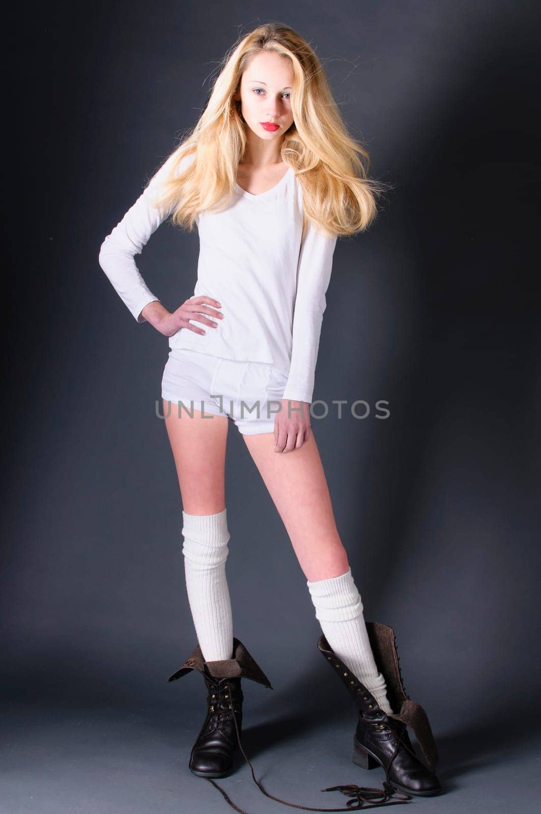 Girl in boyfriend look wears jeans and suspenders and looks over her shoulder into the camera.
