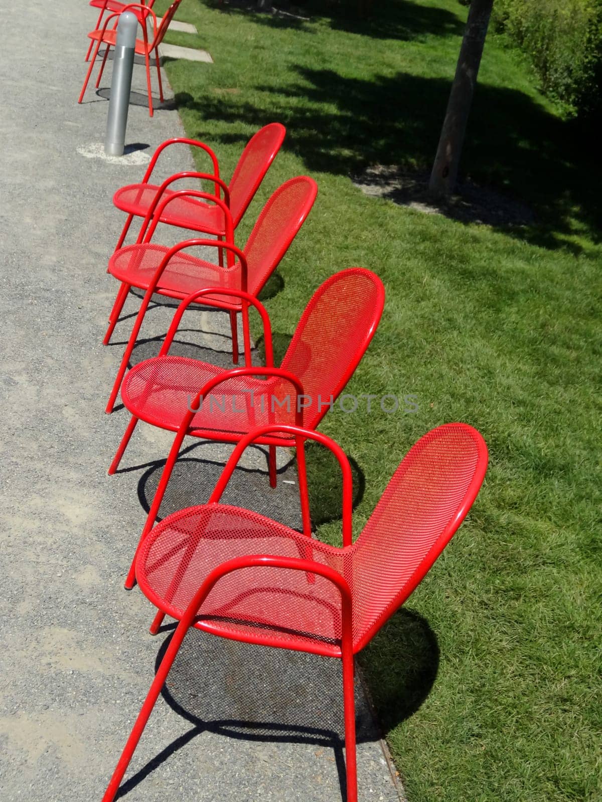 Four empty red metal chairs in a row