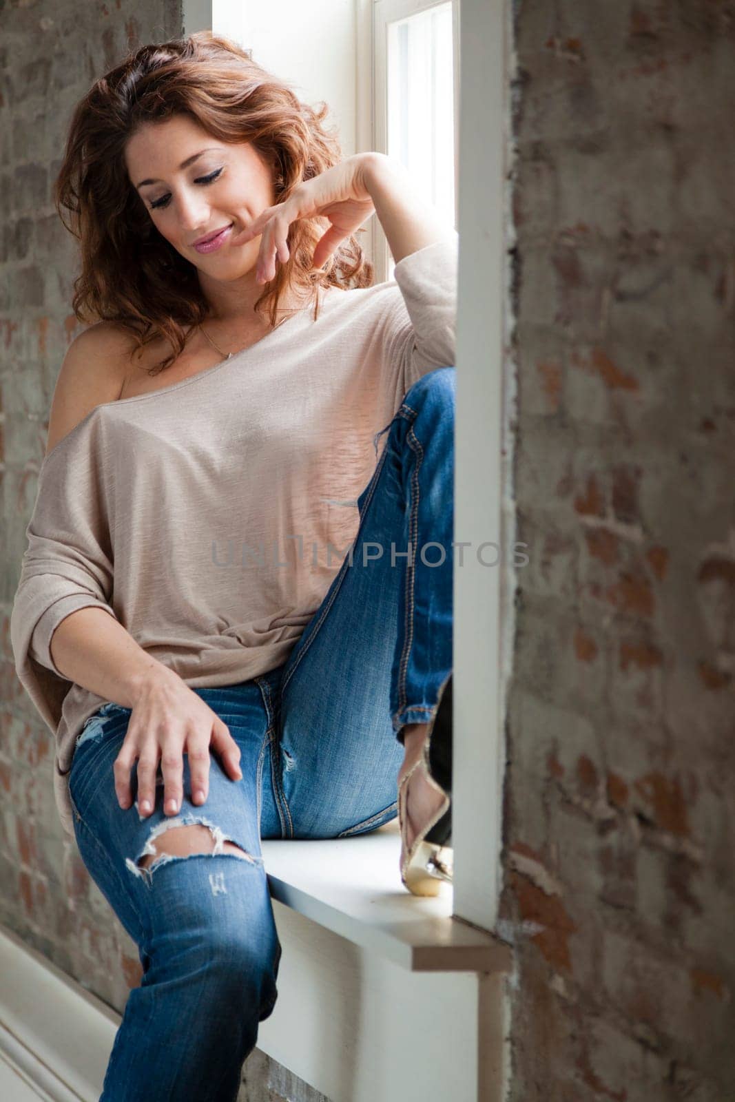 Attractive young woman sitting on the window sill
