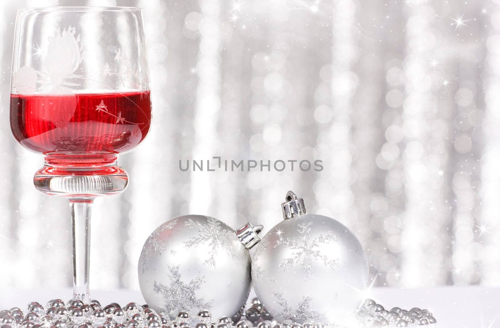 Red wine and Christmas balls against silver background
