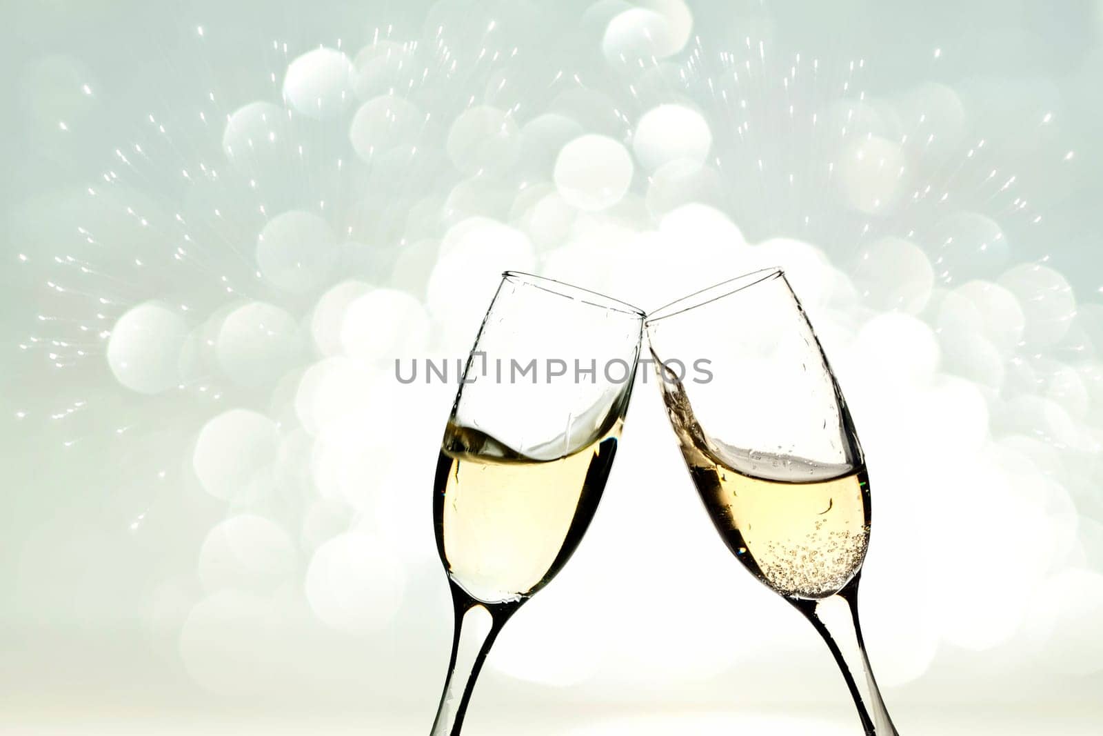Glasses with champagne against holiday light and snowflakes