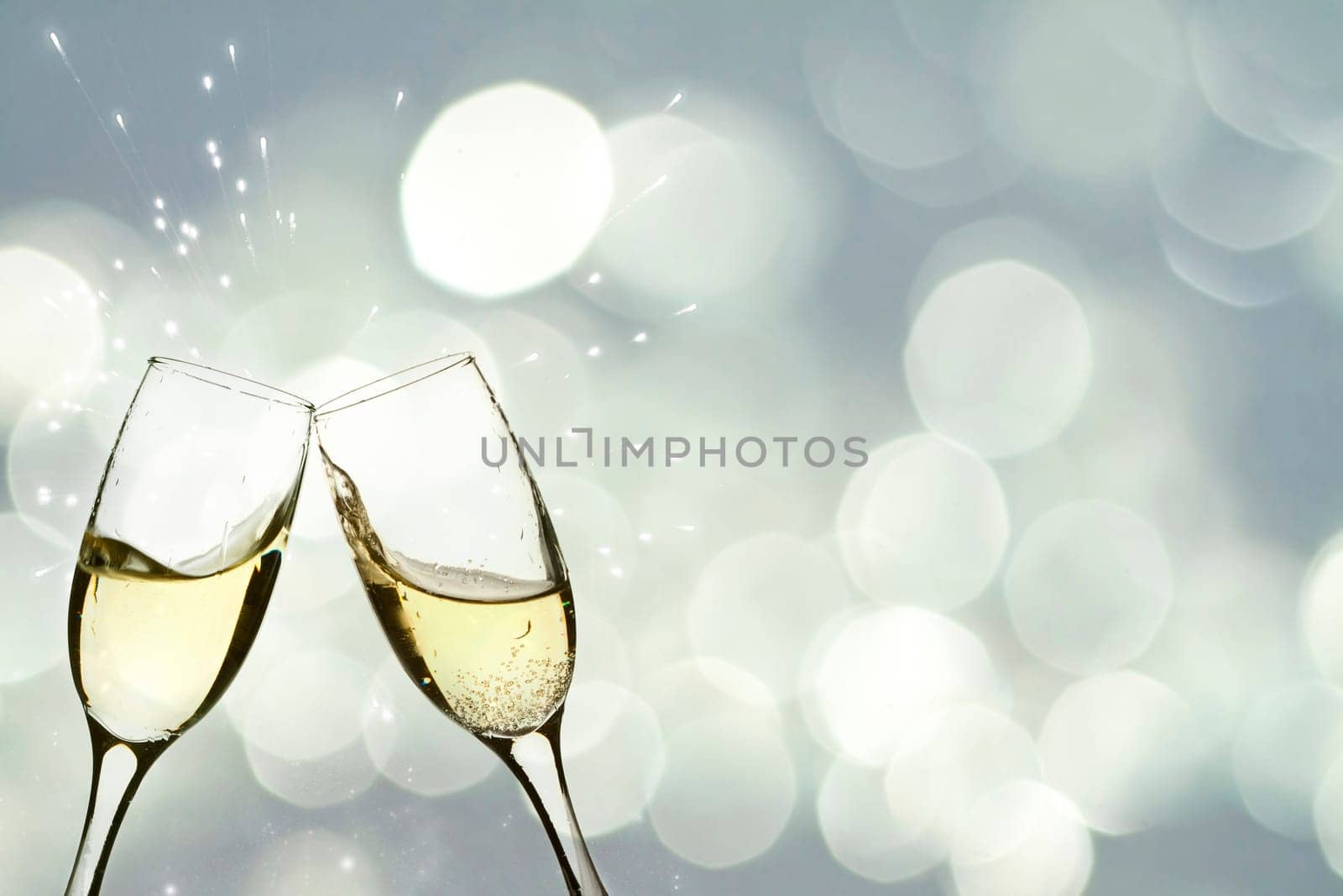 Glasses with champagne against holiday light and snowflakes