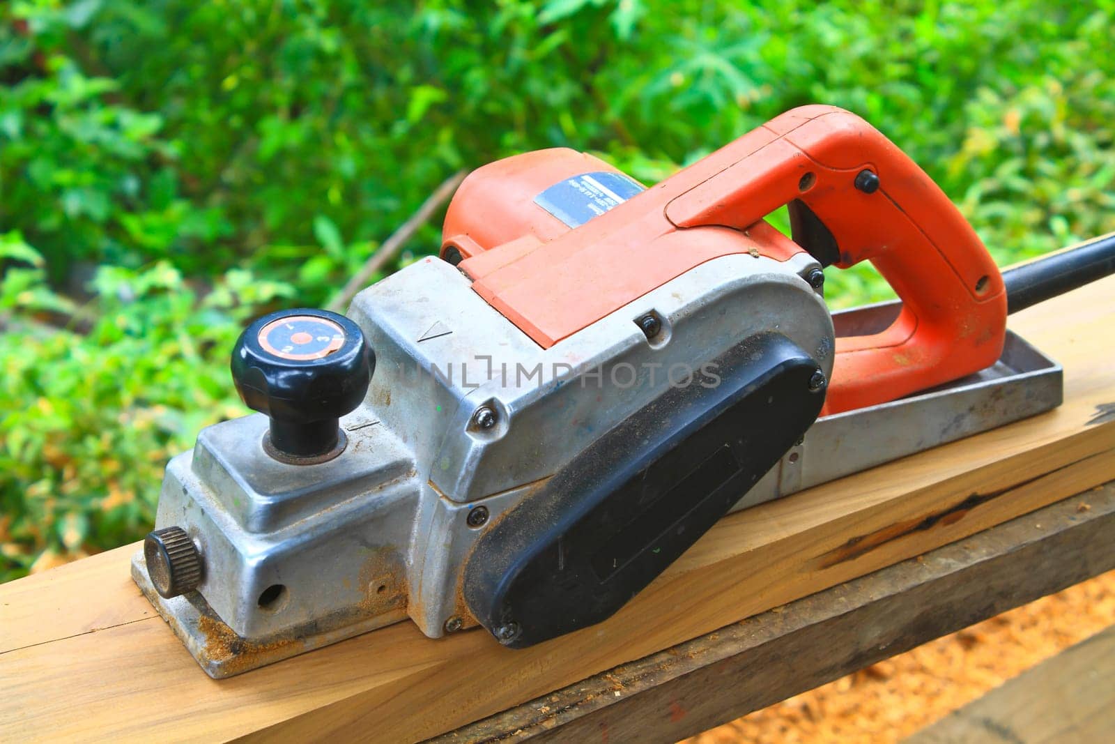 Close up construction worker's hand and power tool while planing a piece of wood trim for a project