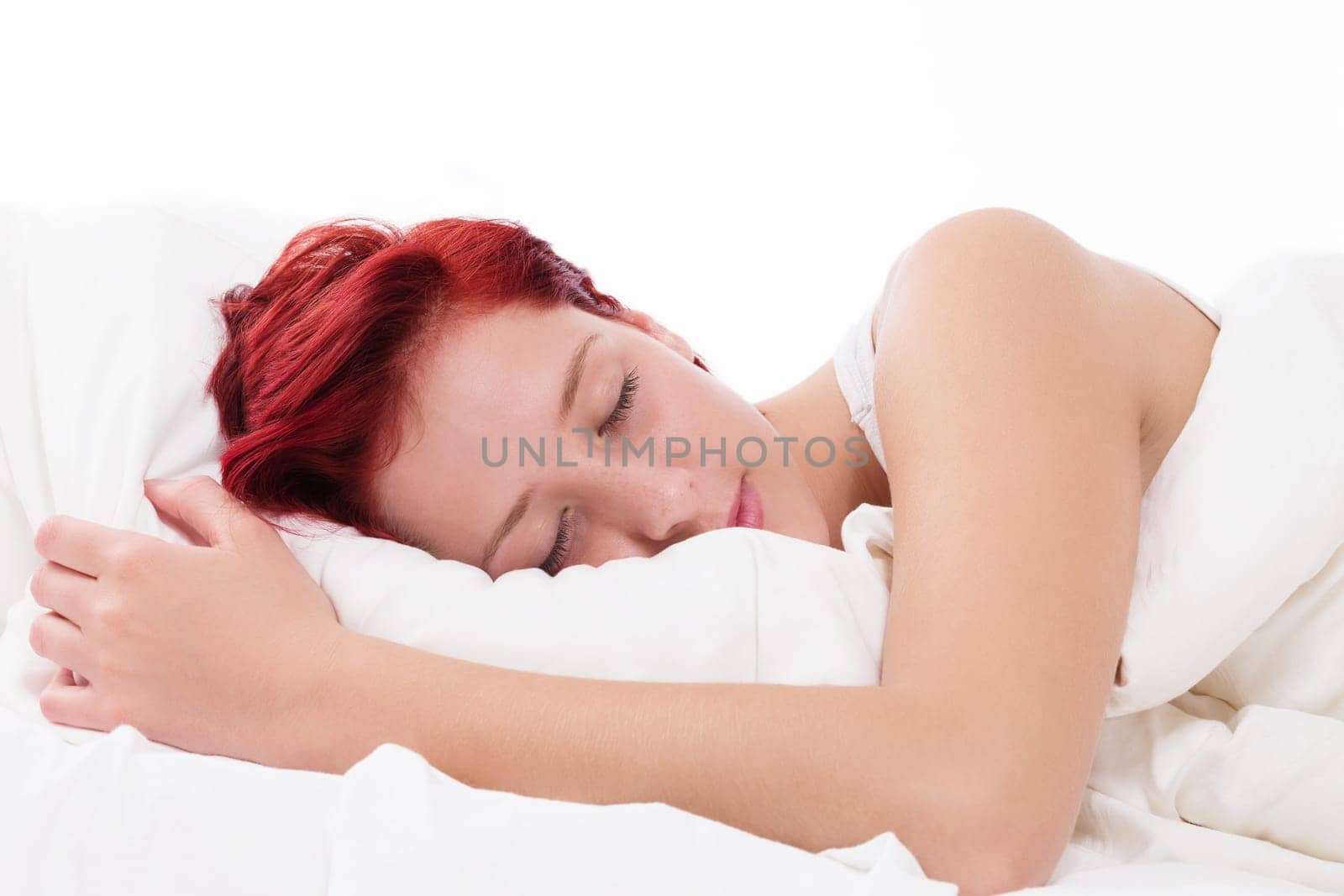Young red-haired woman sleeps in her bed