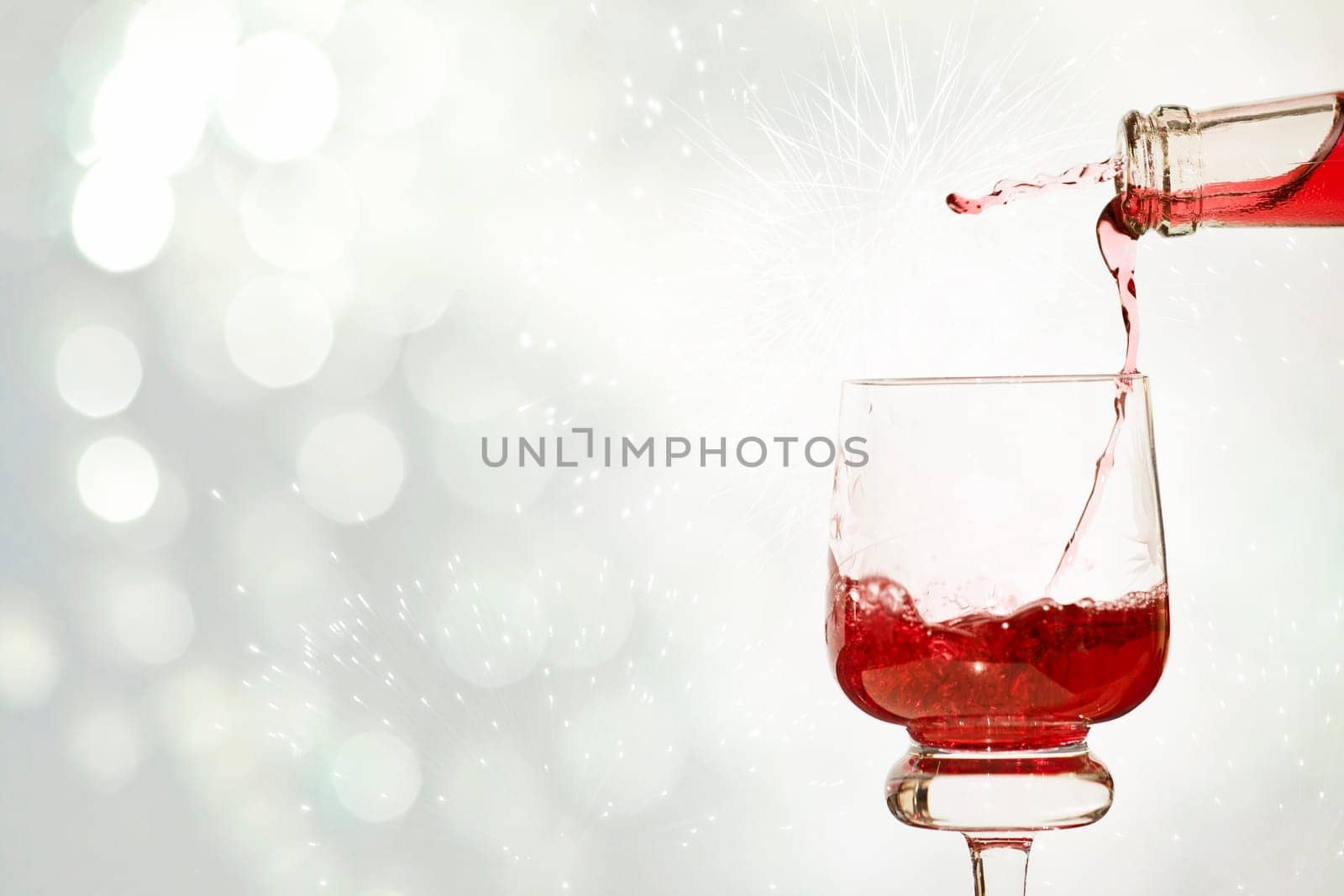 Pouring red wine against festive holiday lights