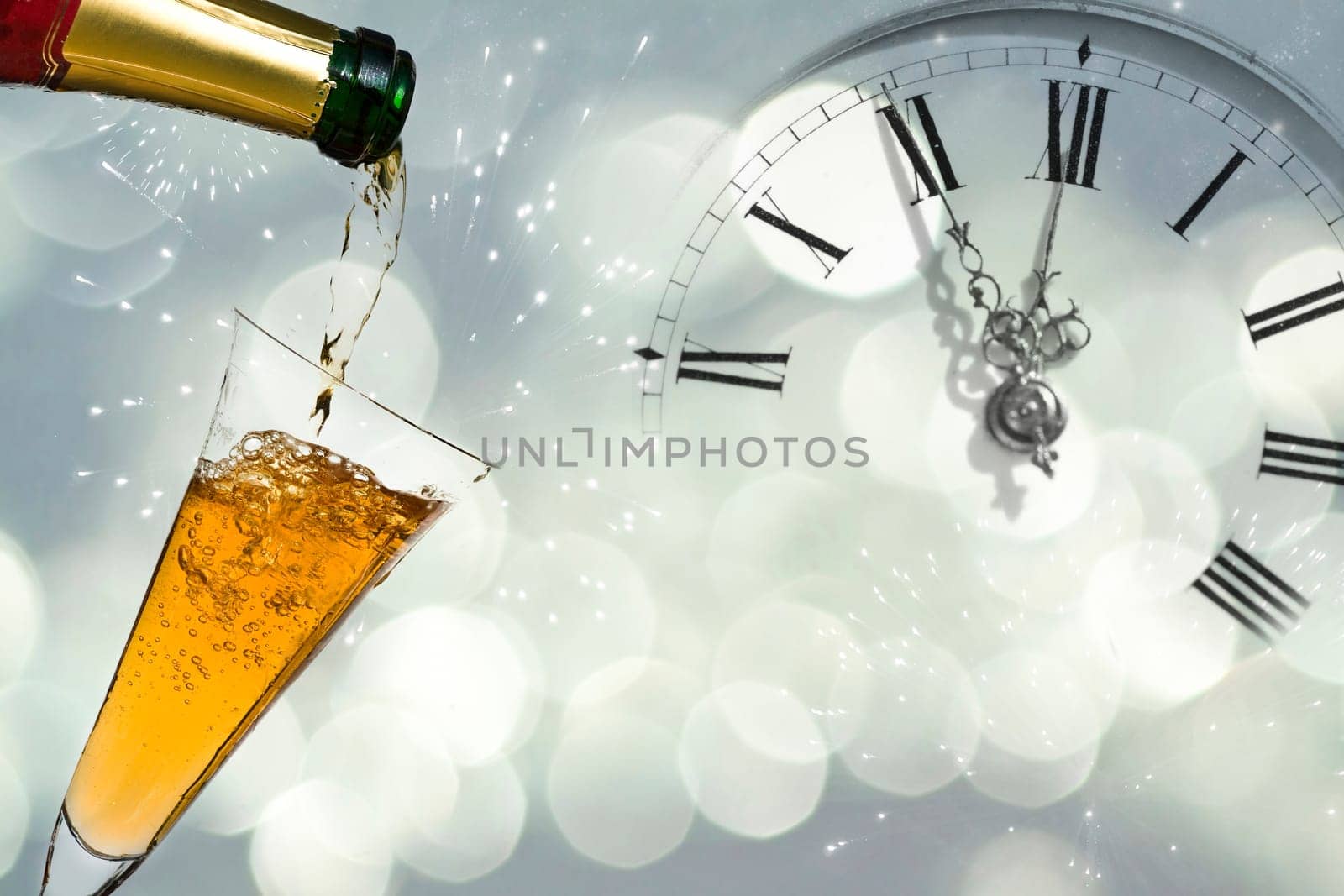 Pouring champagne against holiday lights and clock close to midnight