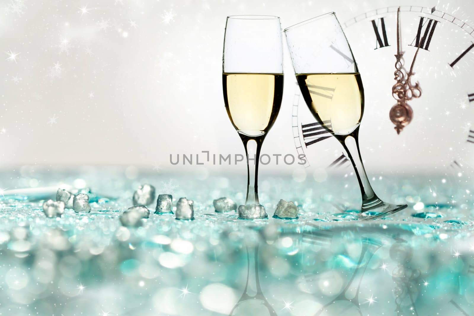 Glasses with champagne against holiday lights and clock close to midnight