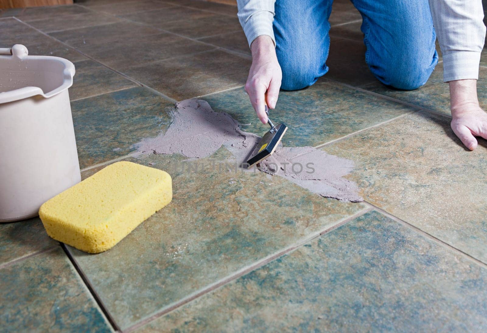 A man repairing the grout on a tile floor