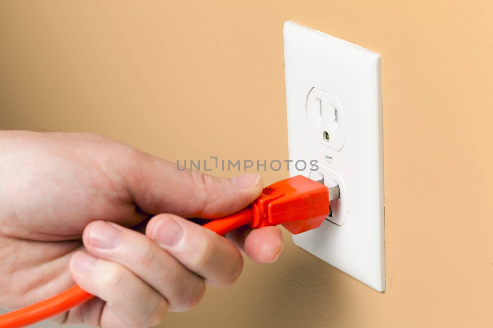 Electrical cord is being plugged into a wall outlet
