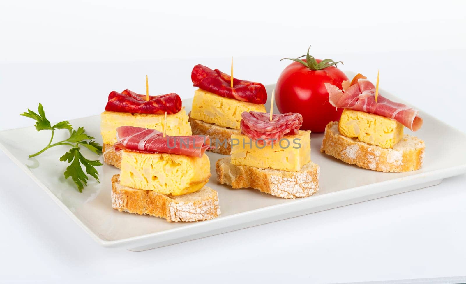 thin slices of Iberian sausage omelette with bread on white base