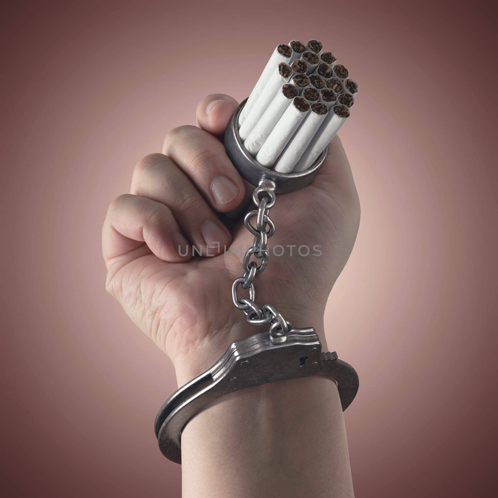 Cigarettes stuck on hand by a handcuff, concept of addiction.