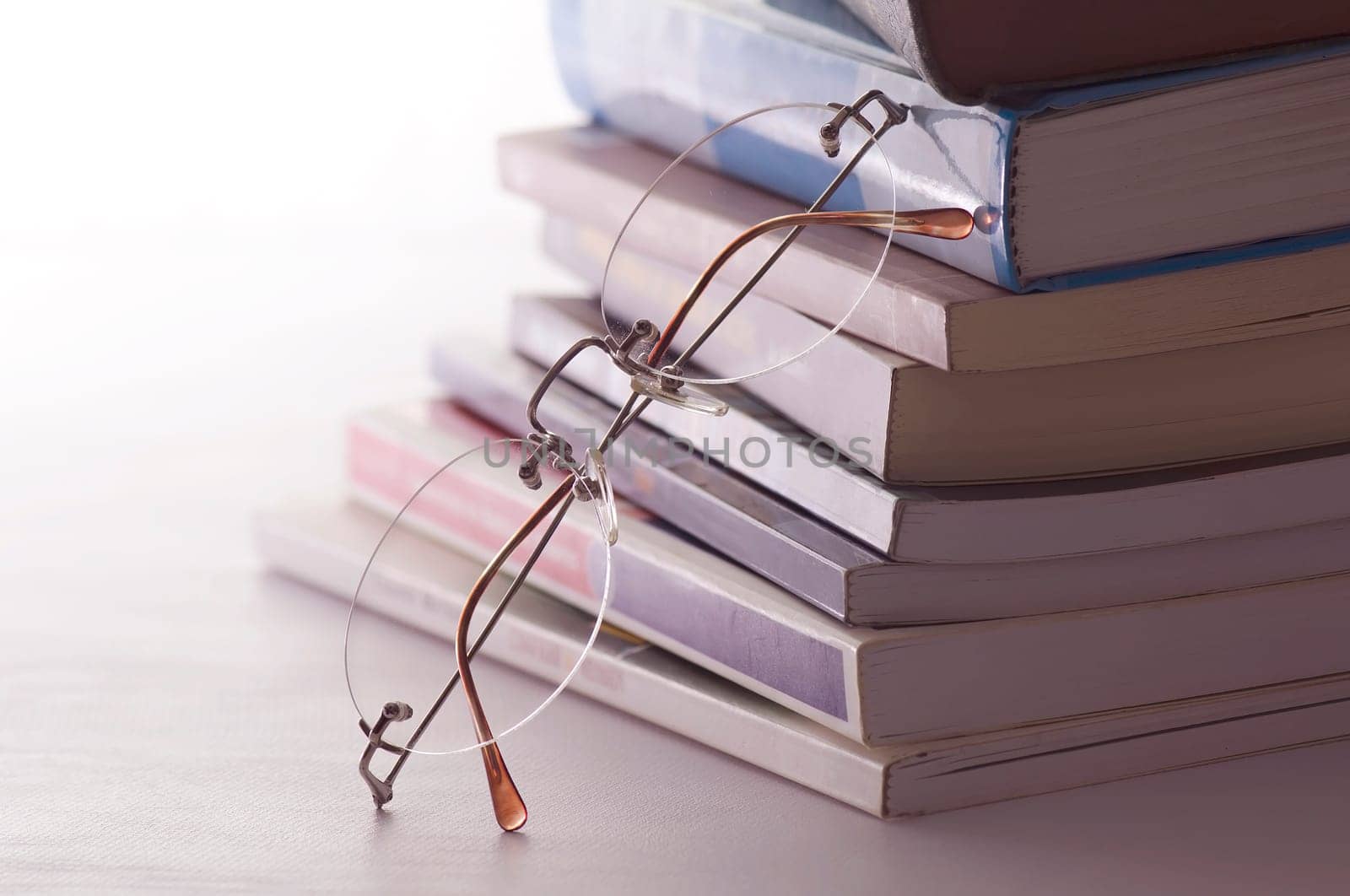 Glasses resting on books. Concept of reading, teacher and student. The image represents the teaching and wisdom.
