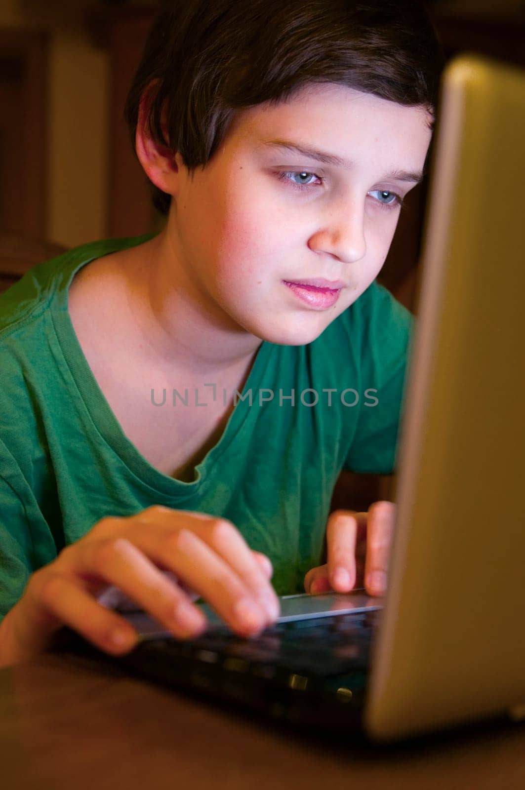 Upper body view of a young male teenager at the table looking at a notebook in a darkened environment