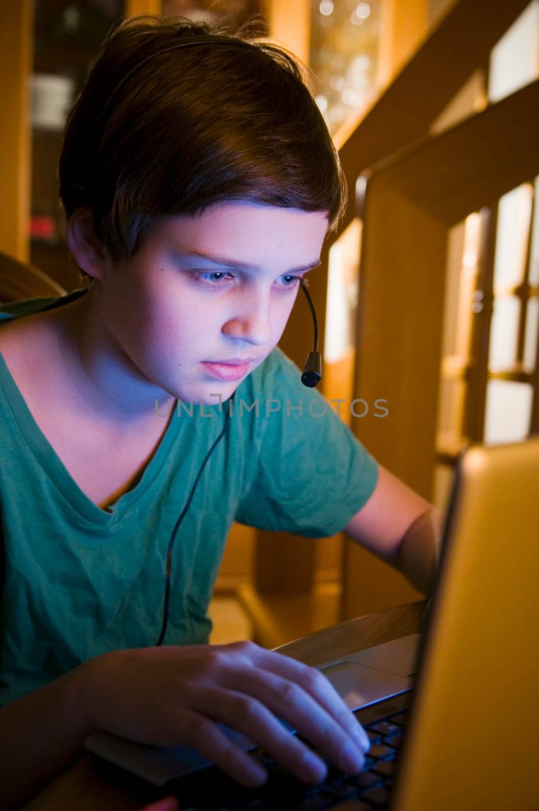 Upper body view of a young male teenager at the table looking at a notebook in a darkened environment