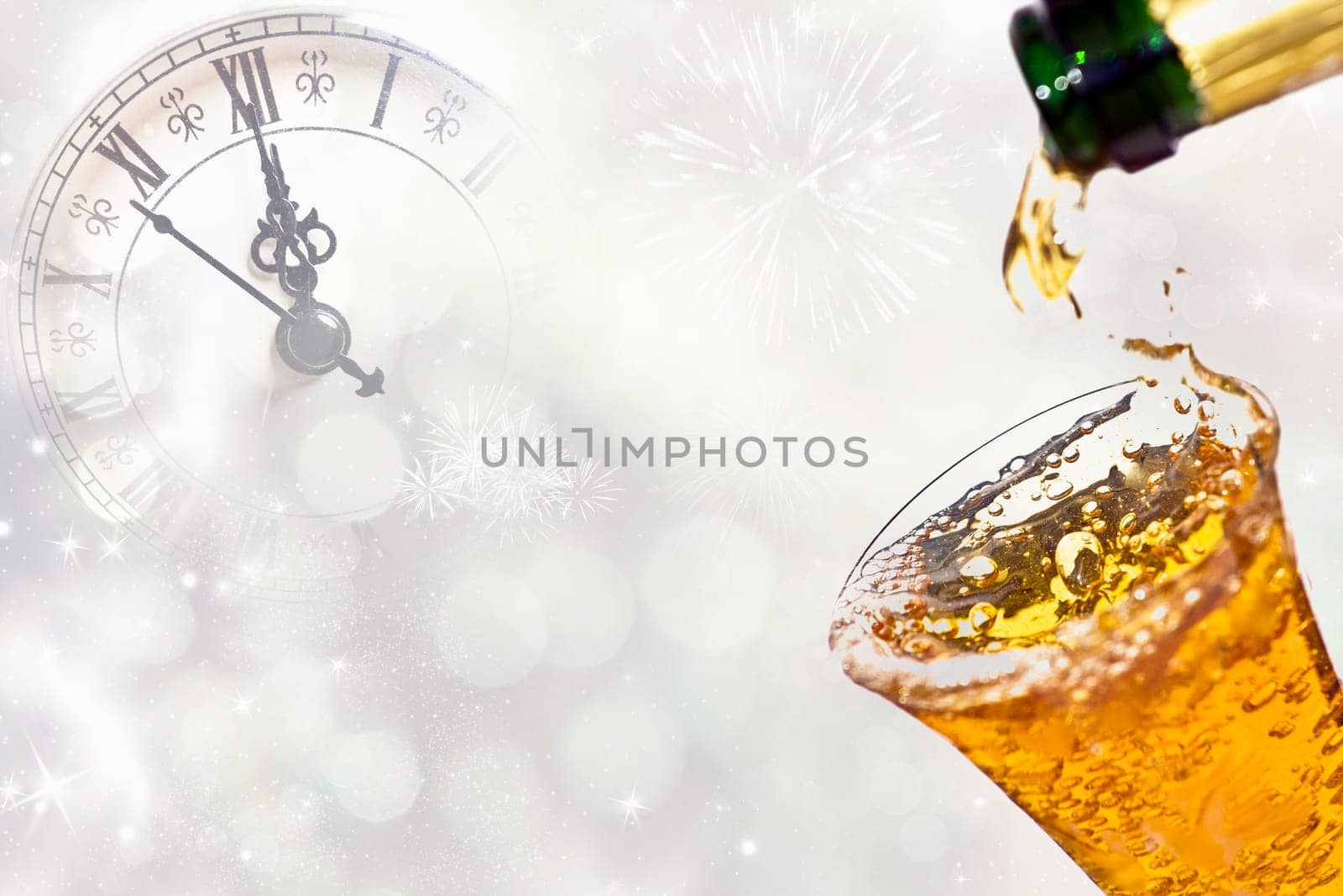 Pouring champagne against holiday lights and clock close to midnight.
