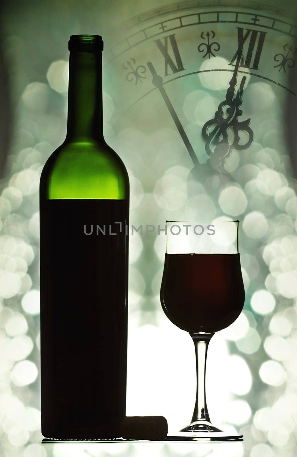 Red wine against holiday lights and clock close to midnight