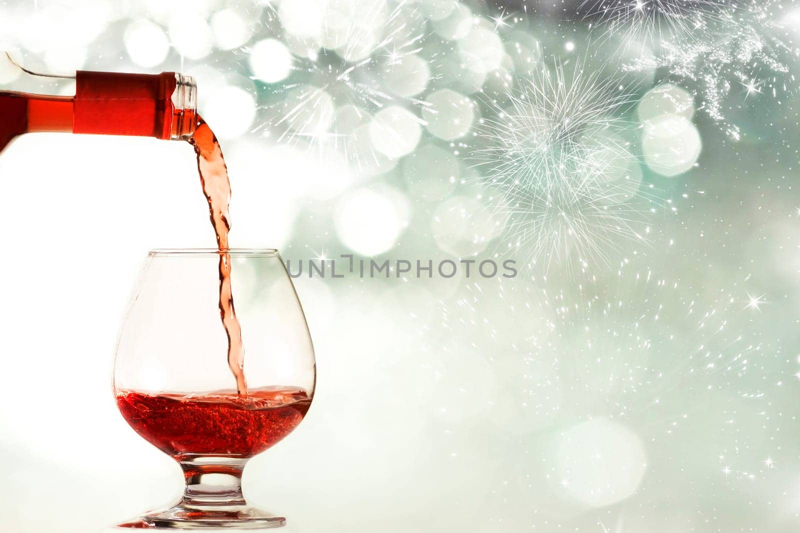 Red wine against silvery fireworks and holiday lights