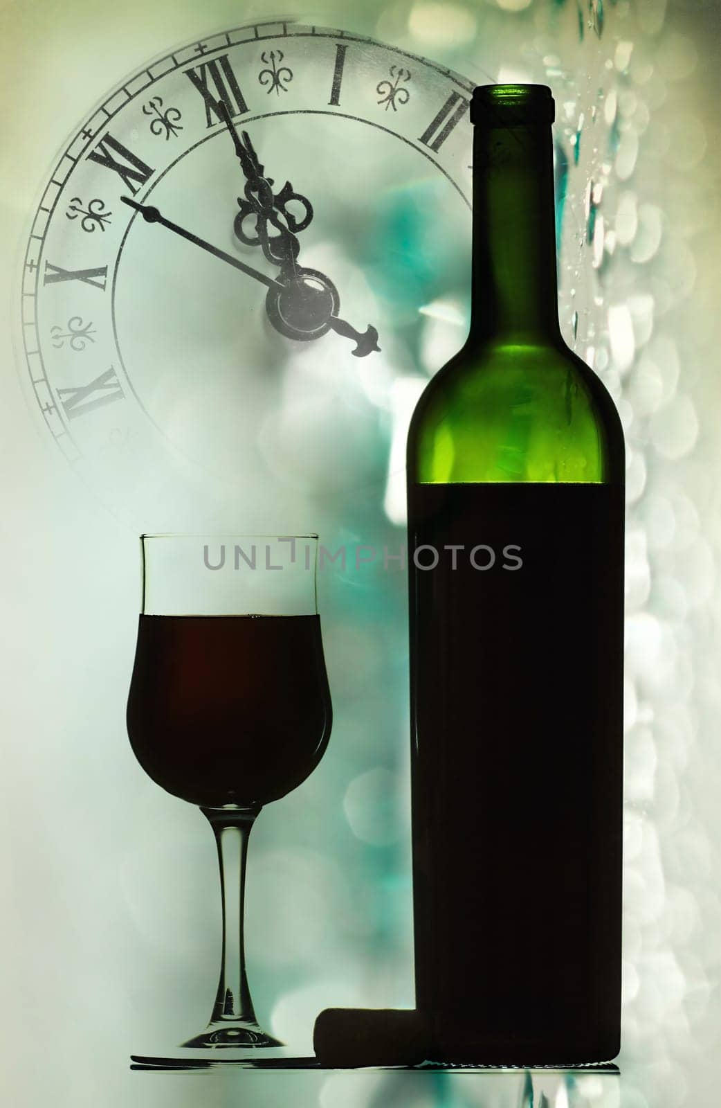 Red wine against holiday lights and clock close to midnight