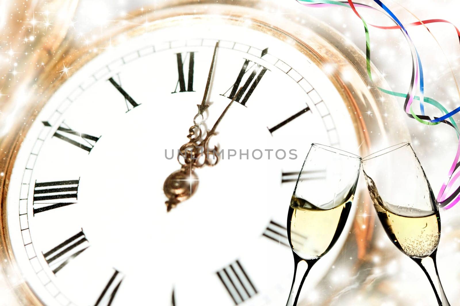 Glasses with champagne against holiday lights and clock close to midnight