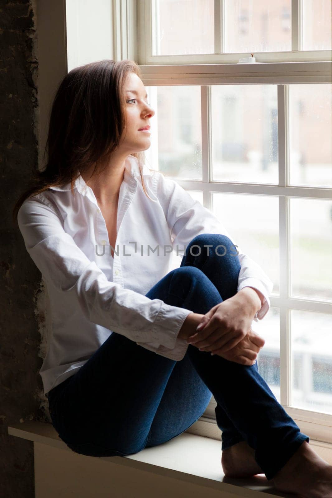 Attractive young woman sitting on the window sill
