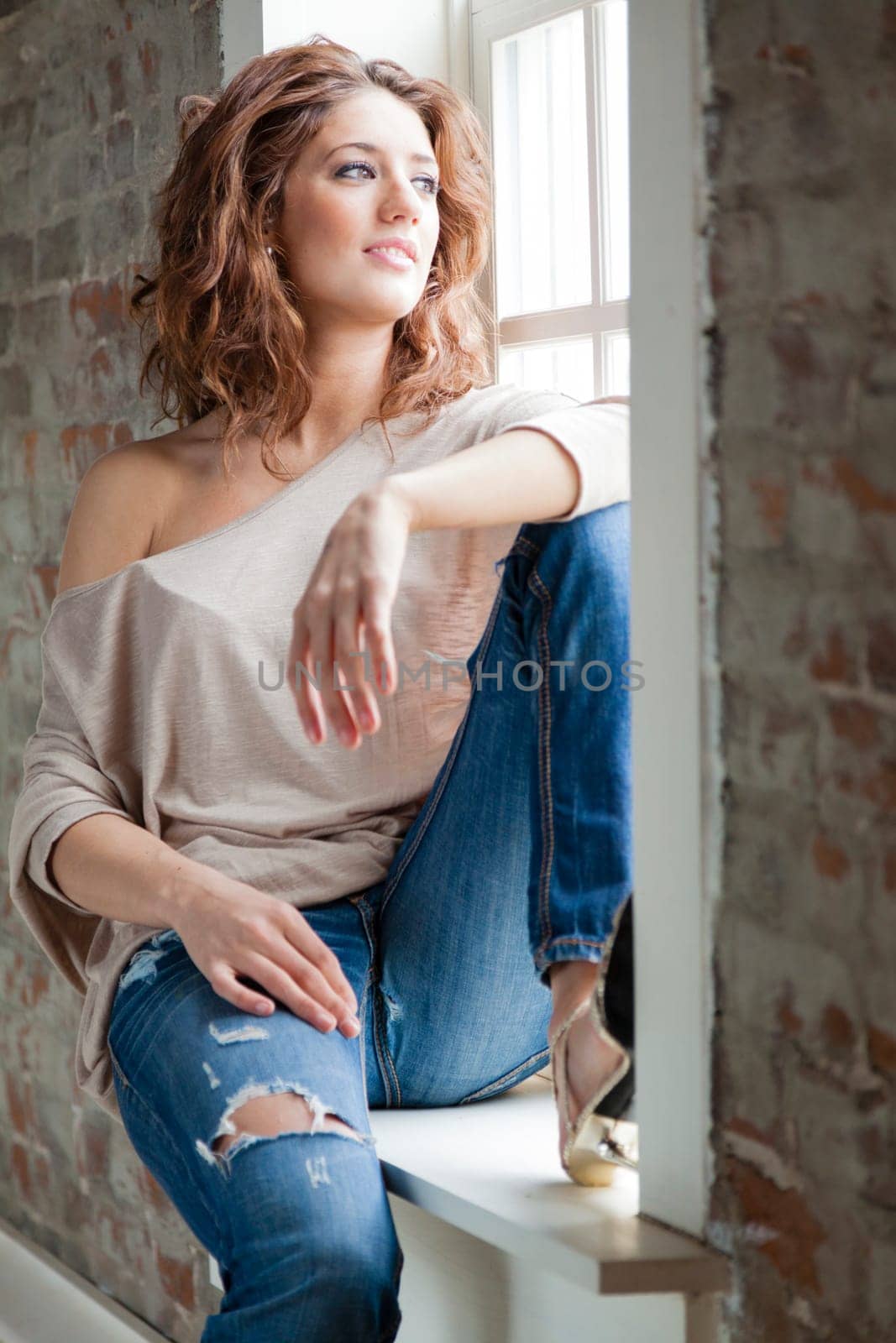 Attractive young woman sitting on the window sill