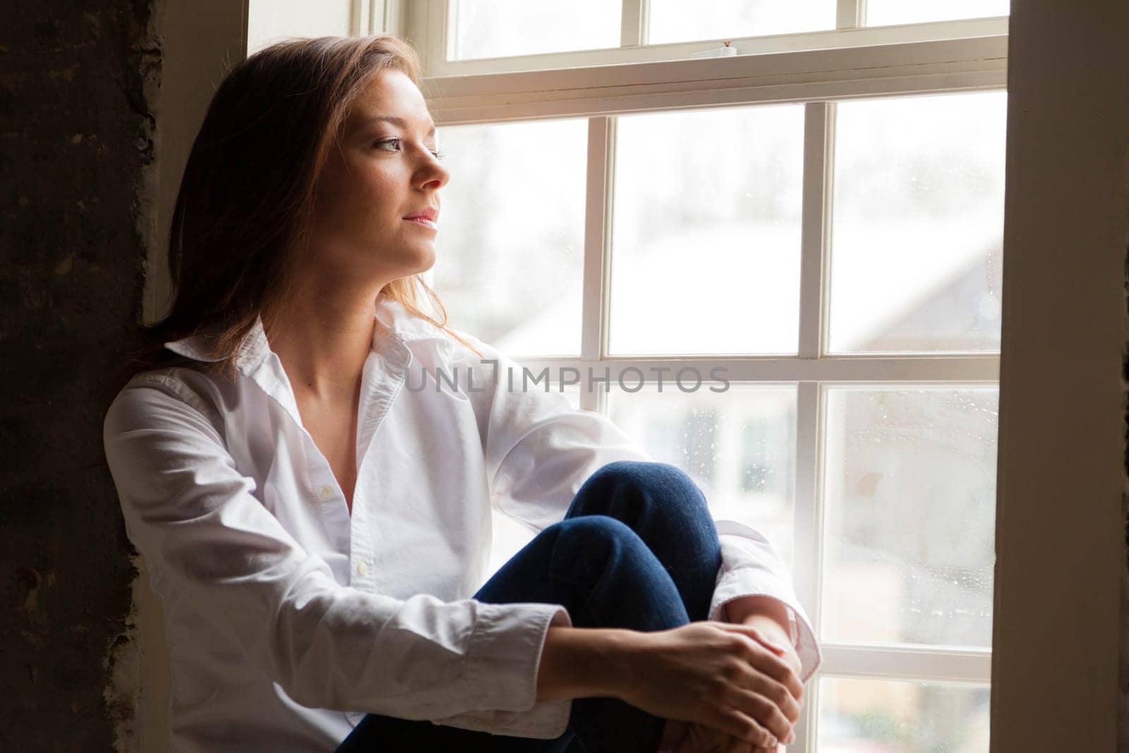 Attractive young woman sitting on the window sill