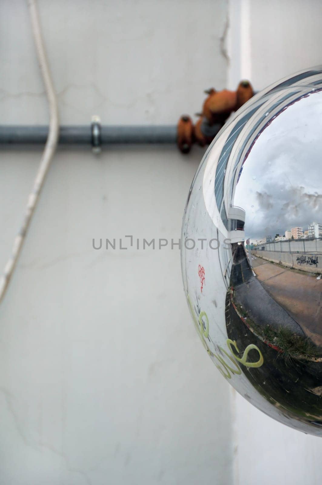 View of cityscape reflected on convex parking mirror. Abstract background.