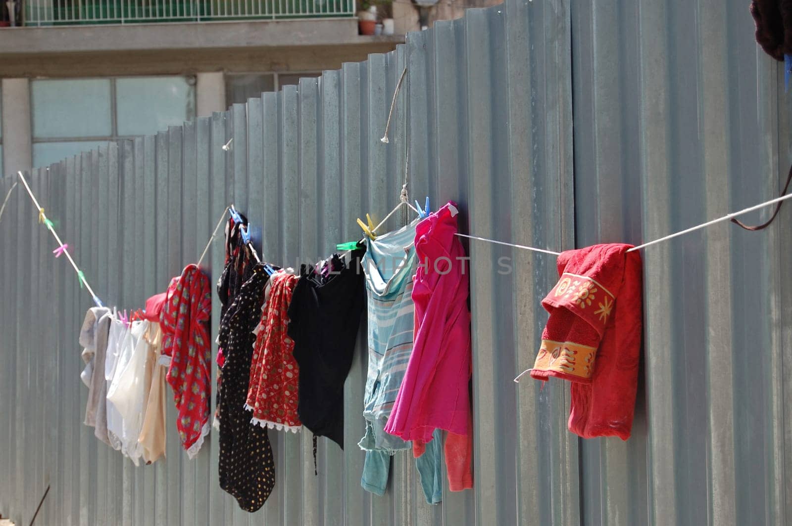 Laundry drying on metal fence. Urban street scene.