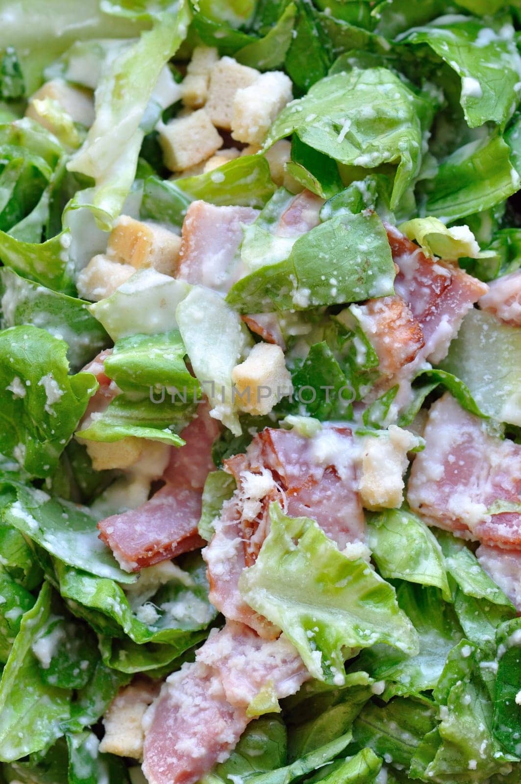 Caesar salad with lettuce, bacon and croutons. Food background.