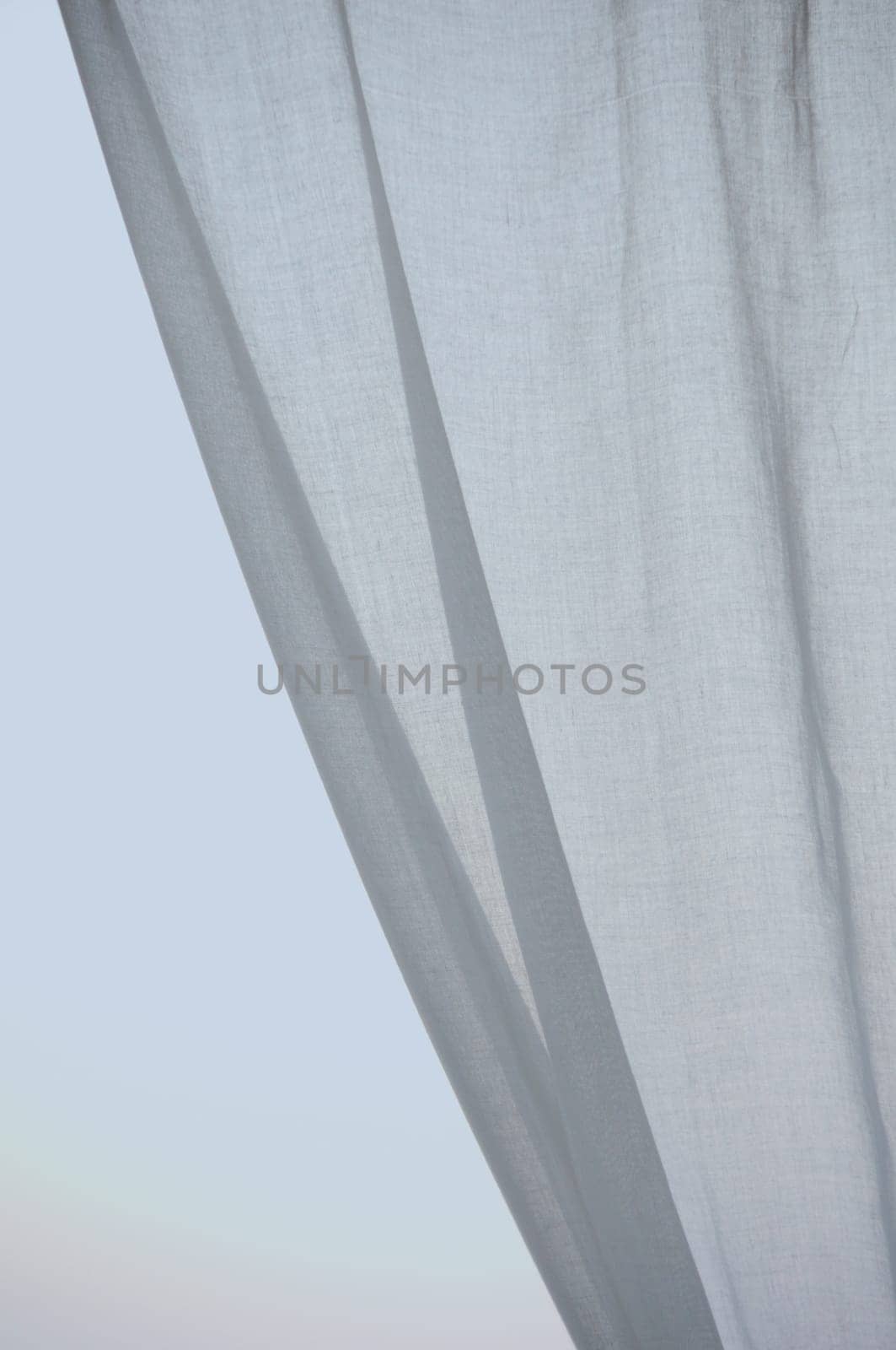 Window curtain against the sky. Folded textile abstract background.