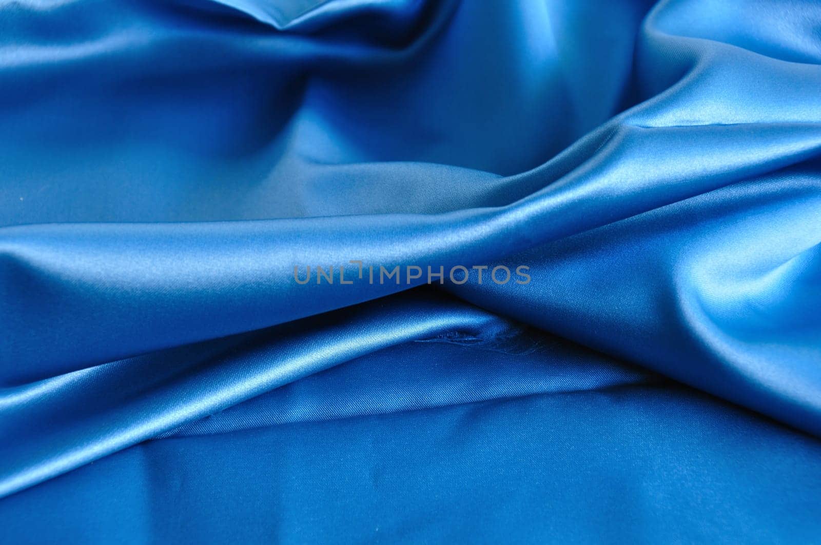 Blue fabric texture. Folded silk textile abstract background.
