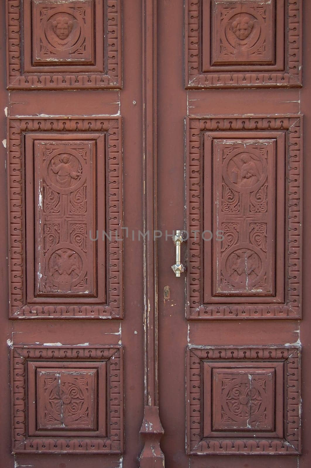 Wooden church door with carved religious symbols. Angels and cross motif.