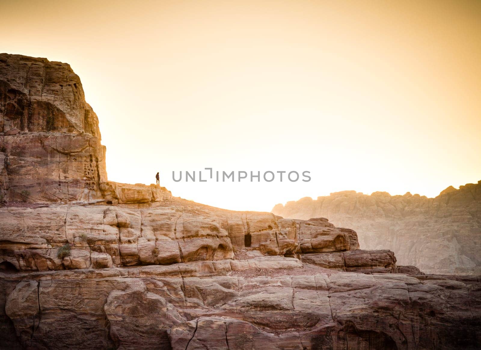 Lone hiker standing on the rock in Petra, Jordan at sunset