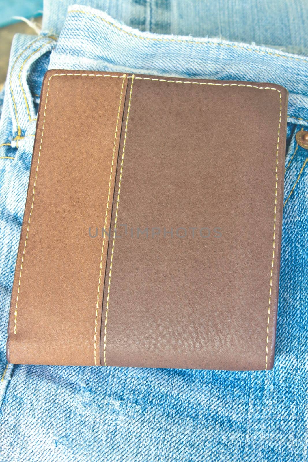 Brown wallet in jeans trousers back pocket, close up texture
