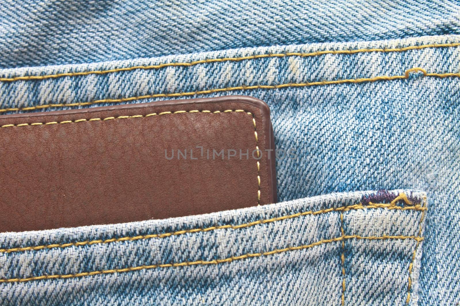 Brown wallet in jeans trousers back pocket, close up texture