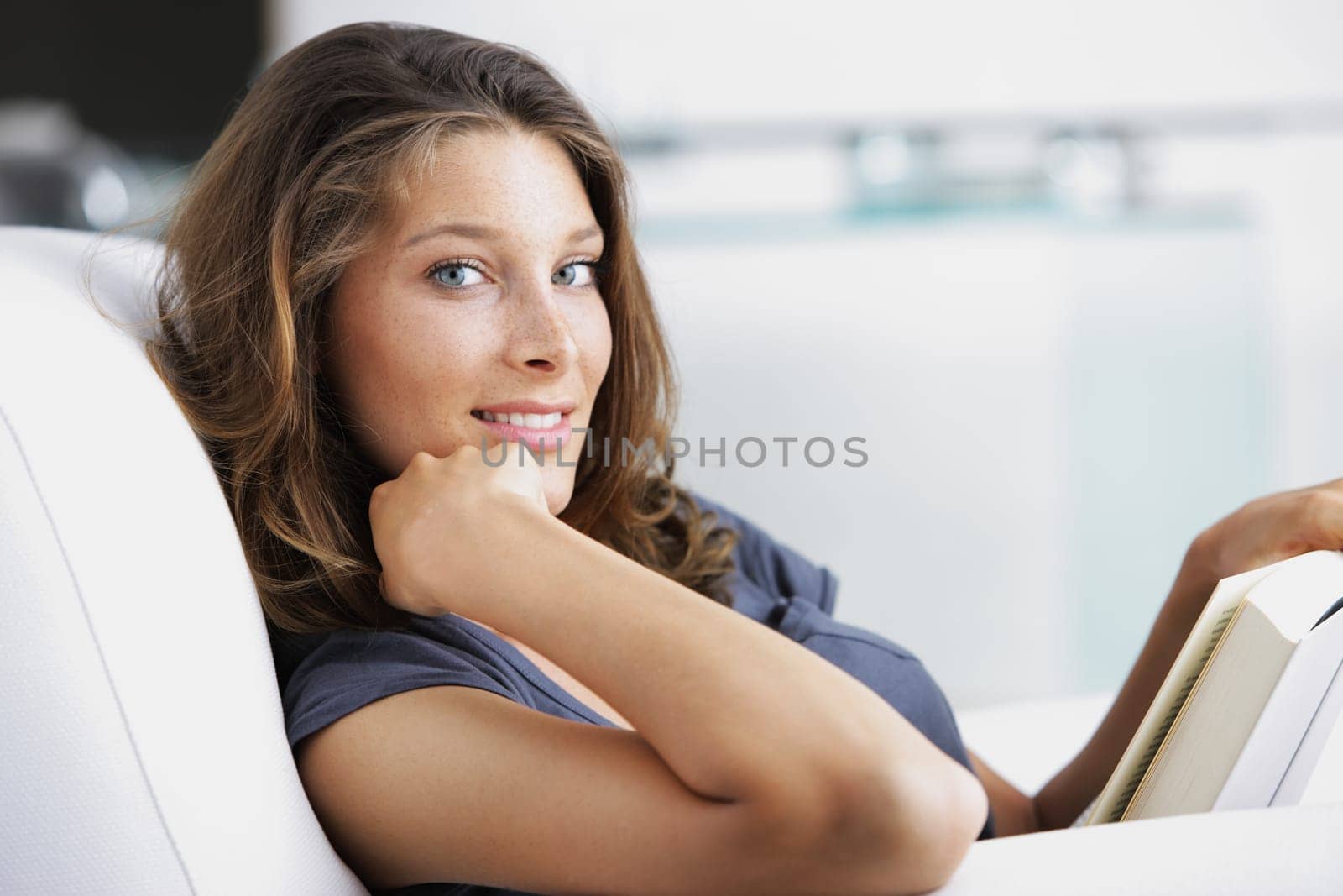 Young beautiful woman reading a book in a white armchair