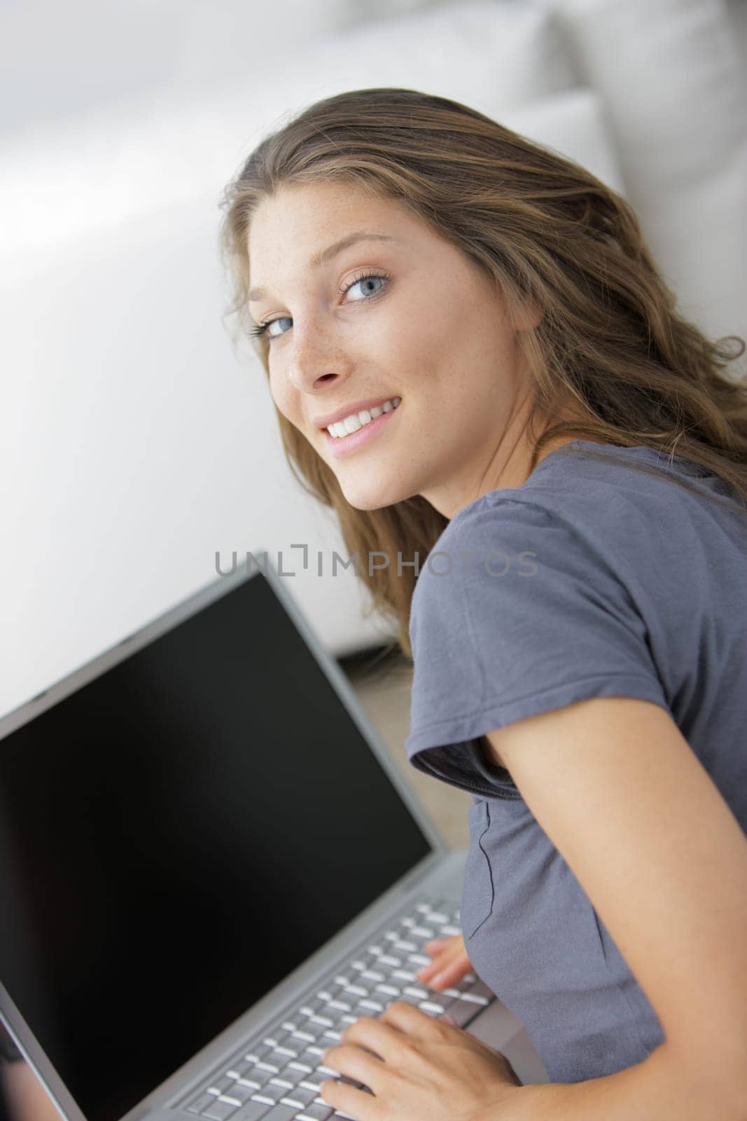 Portrait of a smiling woman browsing on her laptop indoors
