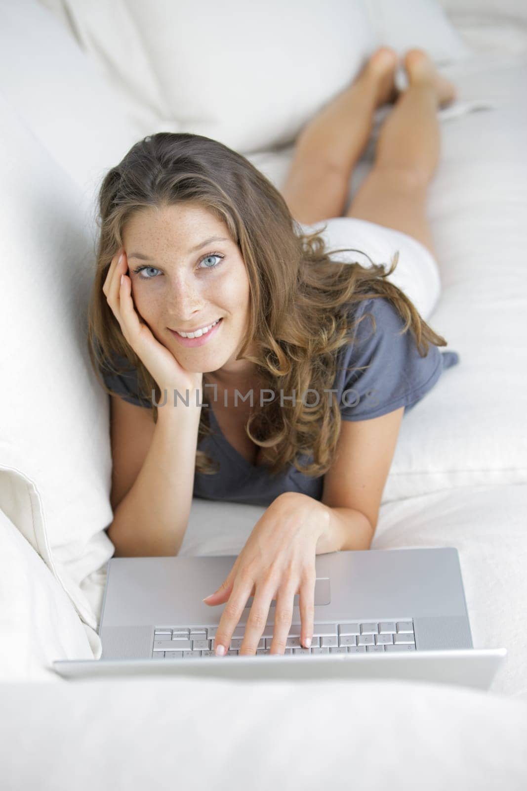 Pretty woman lying on sofa with laptop
