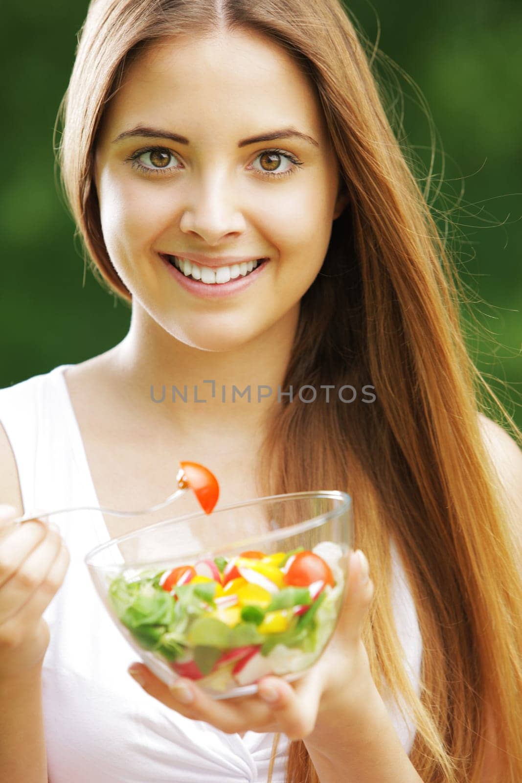 Close-up of happy beautiful young woman eating vegetable salad