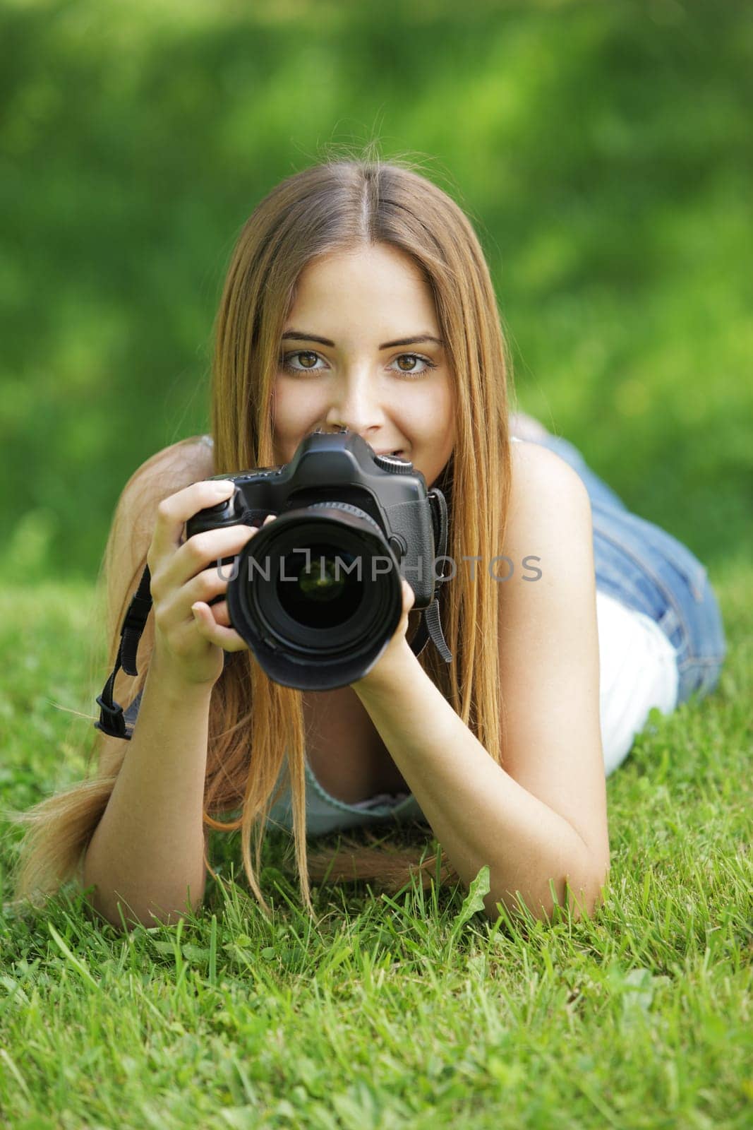 Young woman making photos at summer green park.