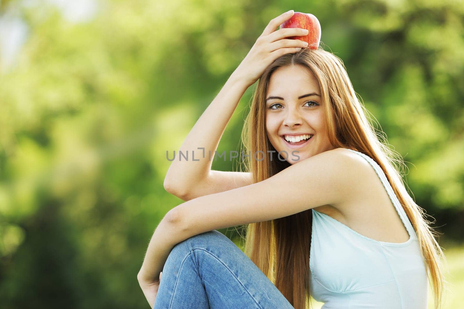Portrait of positive young woman with red apple on her head
