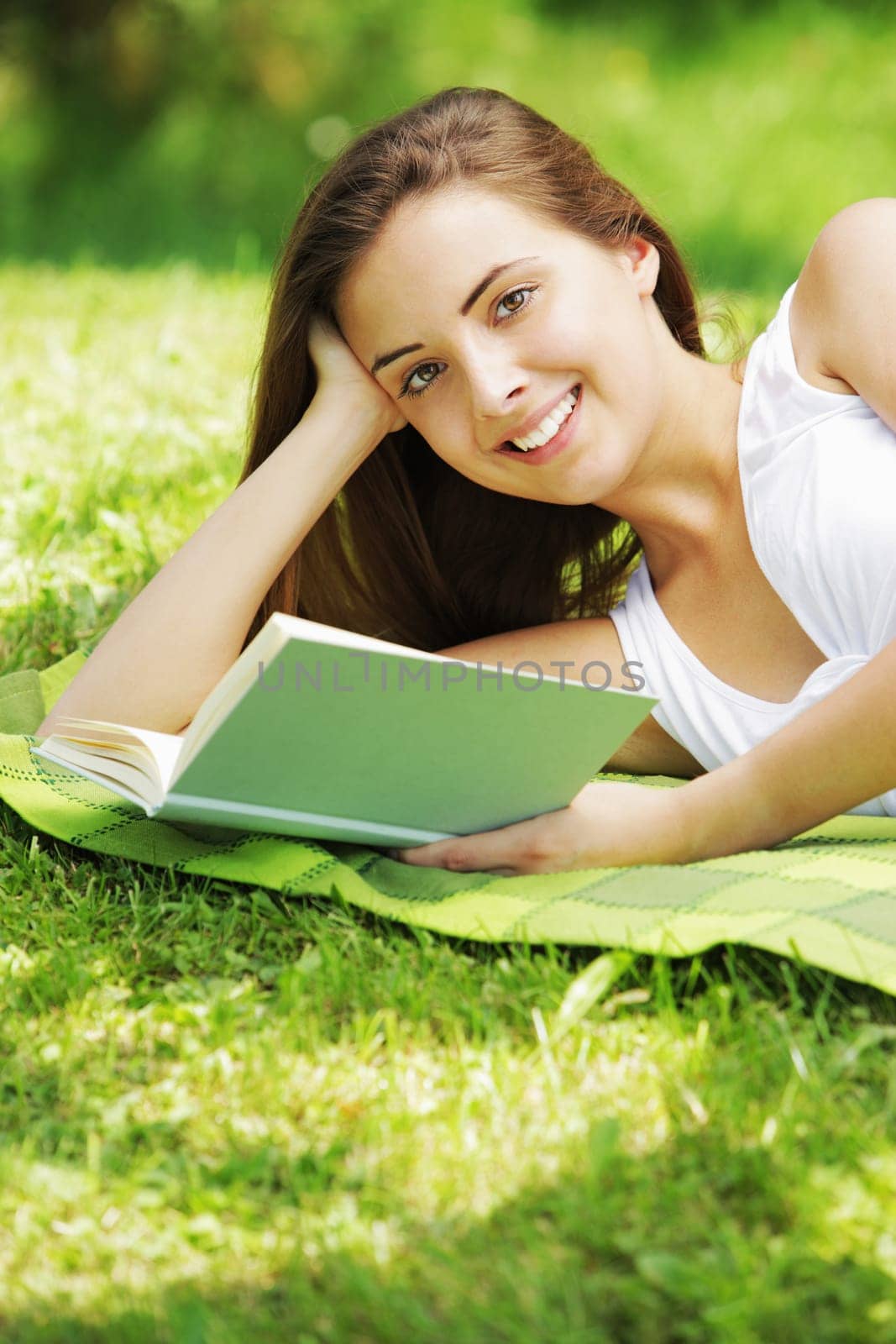 Closeup of a beautiful young woman reading book at park