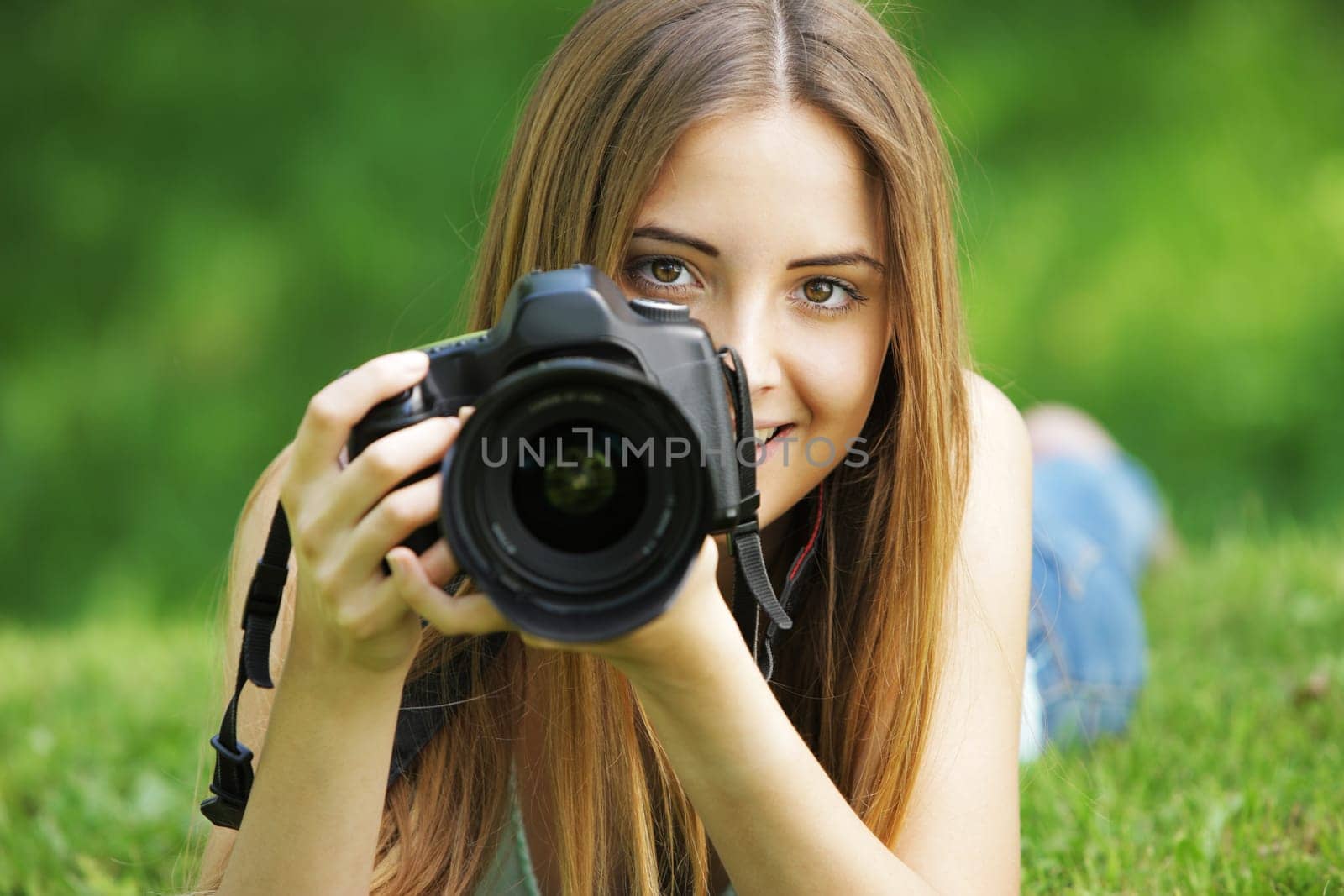 Portrait of beautiful smiling blonde girl , making photos at summer green park.