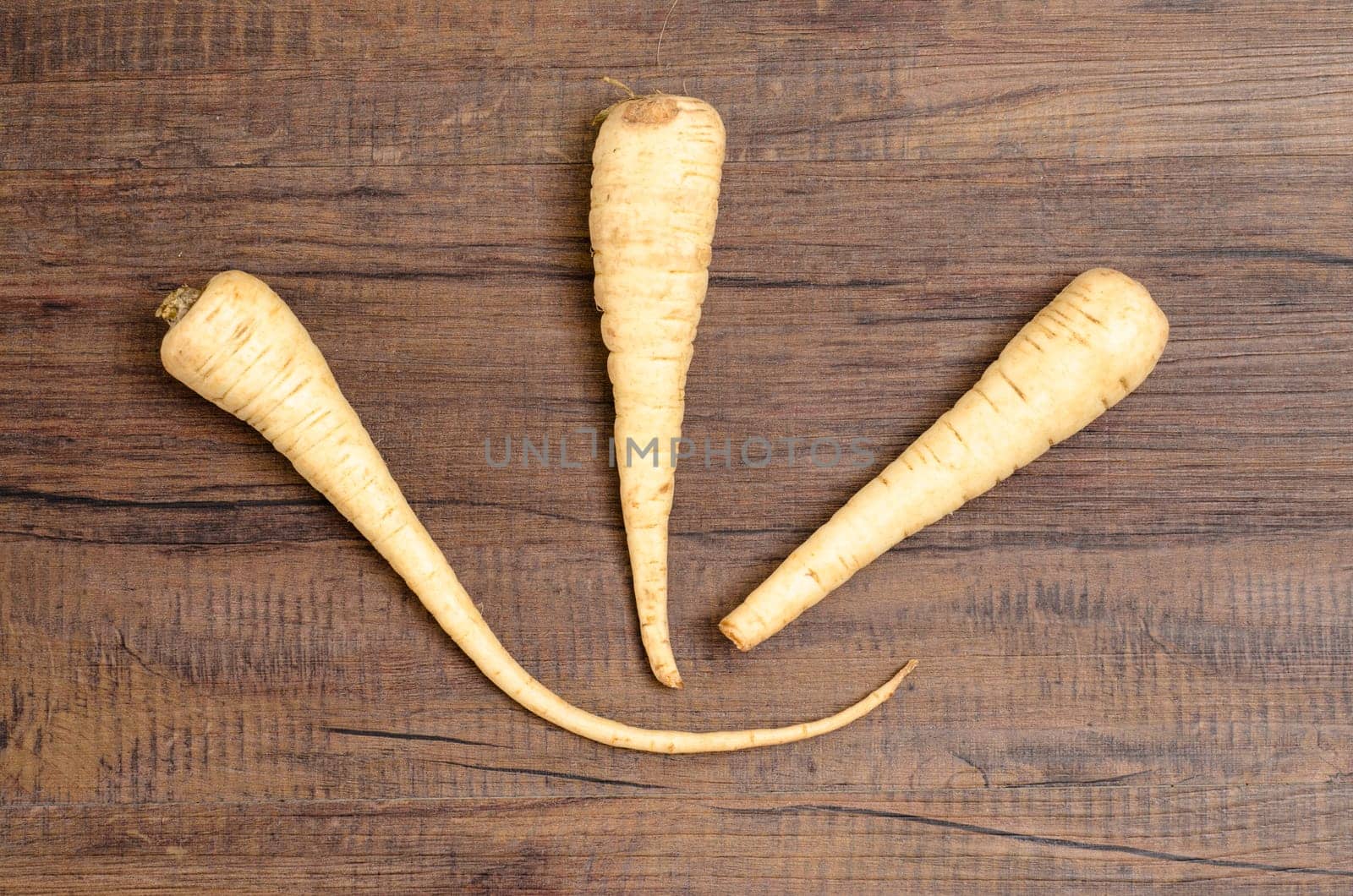 Three parsnips on a brown wood